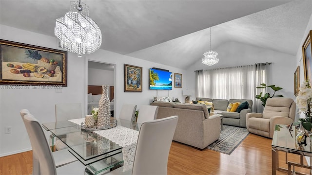 dining space with vaulted ceiling, wood finished floors, baseboards, and a chandelier