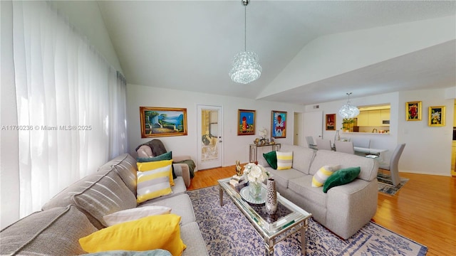 living room featuring vaulted ceiling, a notable chandelier, and wood finished floors