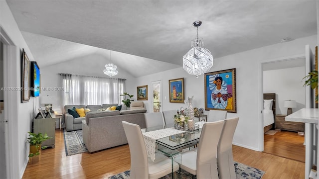 dining area featuring lofted ceiling, a notable chandelier, and light wood-type flooring