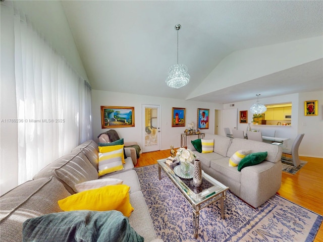 living room featuring a chandelier, lofted ceiling, and wood finished floors