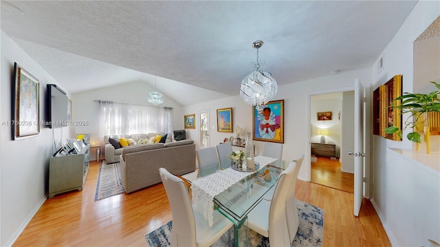 dining room featuring a notable chandelier, visible vents, lofted ceiling, and light wood-style floors