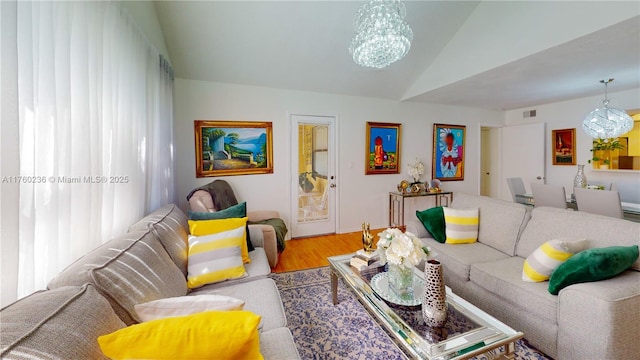 living area featuring a chandelier, lofted ceiling, visible vents, and wood finished floors