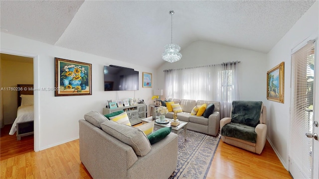 living area with baseboards, lofted ceiling, a textured ceiling, a notable chandelier, and light wood-type flooring