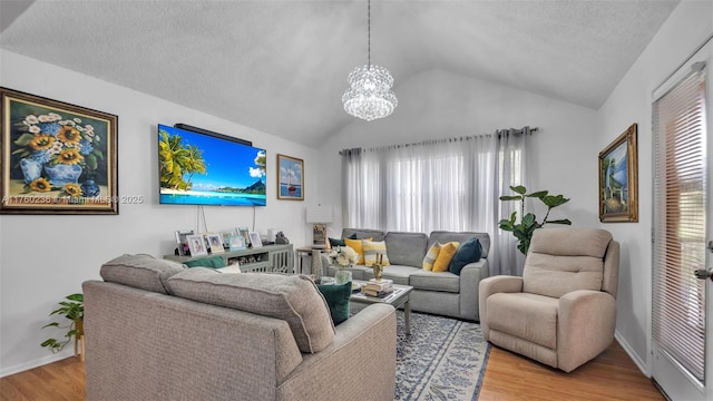 living room featuring baseboards, vaulted ceiling, light wood-style flooring, a notable chandelier, and a textured ceiling