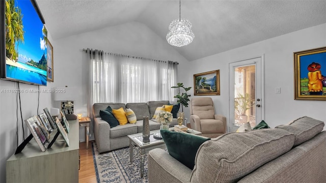 living room with an inviting chandelier, light wood-style flooring, a textured ceiling, and lofted ceiling