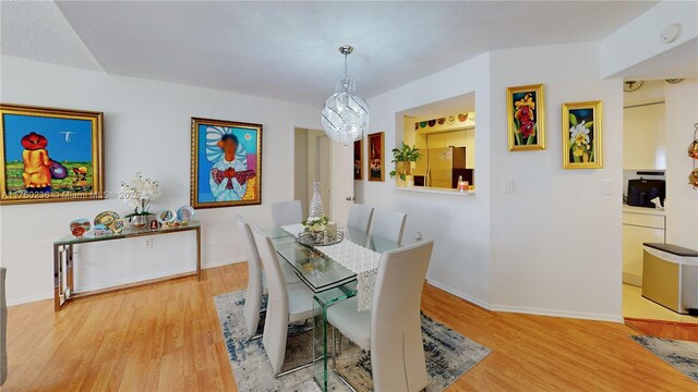 dining space with a chandelier, baseboards, and wood finished floors