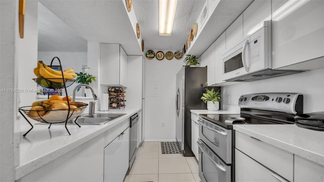 kitchen featuring appliances with stainless steel finishes, white cabinetry, and a sink
