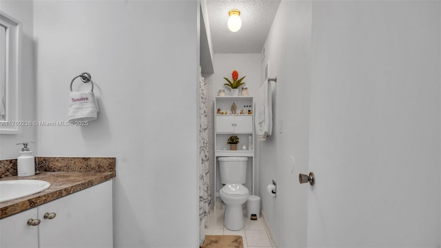 bathroom with tile patterned flooring, toilet, vanity, and a textured ceiling