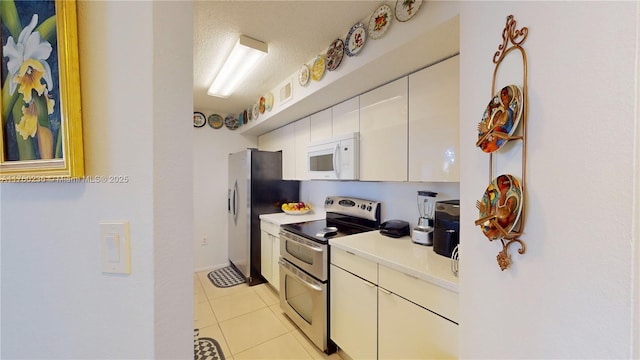 kitchen with light tile patterned floors, white cabinetry, appliances with stainless steel finishes, and light countertops