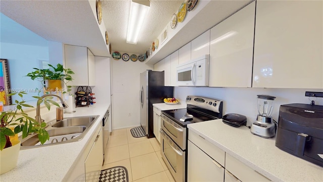kitchen with a sink, a textured ceiling, white cabinetry, and stainless steel appliances