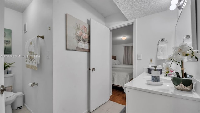 ensuite bathroom with visible vents, toilet, vanity, ensuite bath, and a textured ceiling