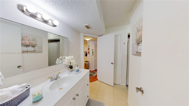 bathroom with tile patterned flooring, vanity, visible vents, and a textured ceiling