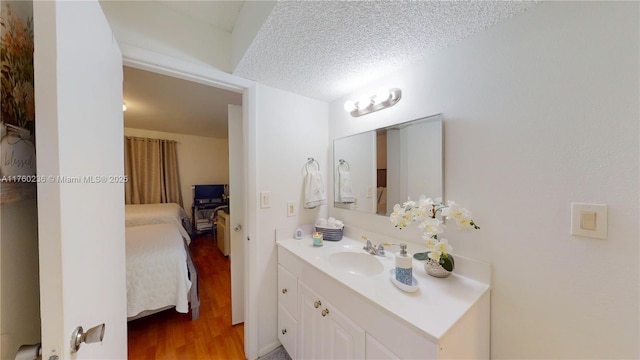 bathroom featuring vanity, wood finished floors, ensuite bathroom, and a textured ceiling