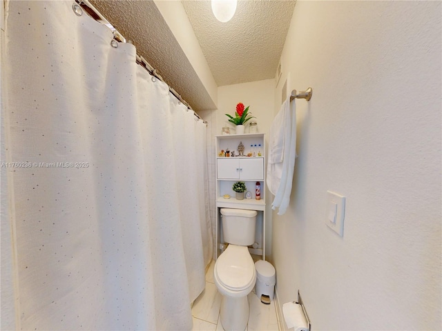 bathroom with tile patterned flooring, toilet, and a textured ceiling