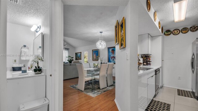15591 SW 105th Ter Unit 524, Miami, FL 33196 - kitchen with a textured ceiling, stainless steel dishwasher, lofted ceiling, a chandelier, and light wood finished floors