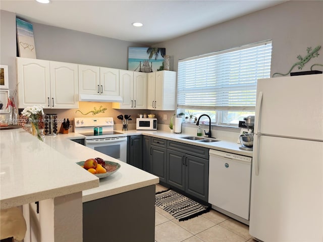 kitchen with gray cabinetry, a sink, under cabinet range hood, white appliances, and white cabinets