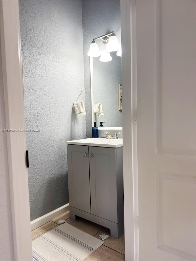 bathroom featuring vanity, a textured wall, and baseboards