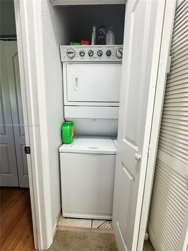 laundry room featuring baseboards, stacked washer and clothes dryer, and laundry area