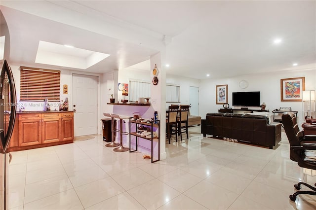 living area featuring recessed lighting, a raised ceiling, arched walkways, and light tile patterned flooring