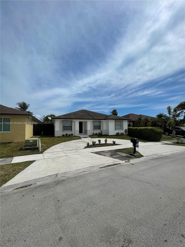 view of front facade featuring concrete driveway and fence