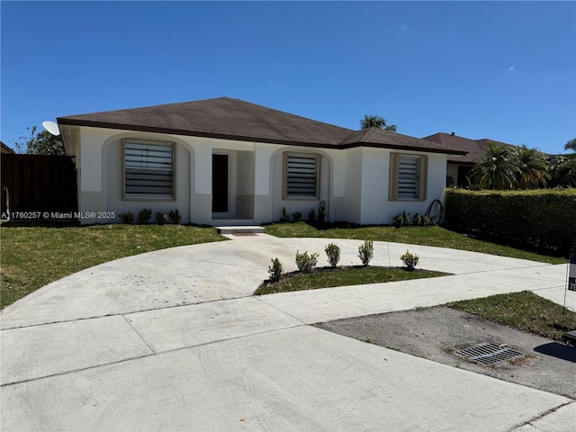 view of front of property featuring a front lawn, curved driveway, and stucco siding