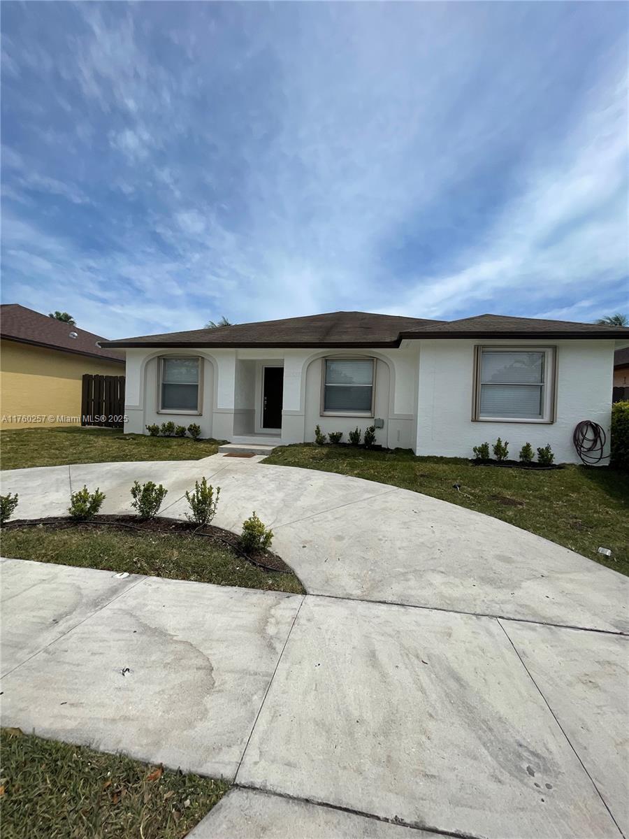 ranch-style house with a front lawn and stucco siding