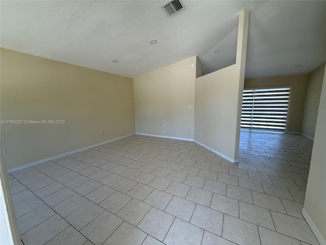 unfurnished room featuring baseboards, vaulted ceiling, visible vents, and light tile patterned floors