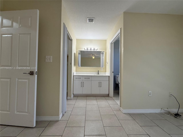 bathroom with tile patterned floors, a textured ceiling, toilet, baseboards, and visible vents
