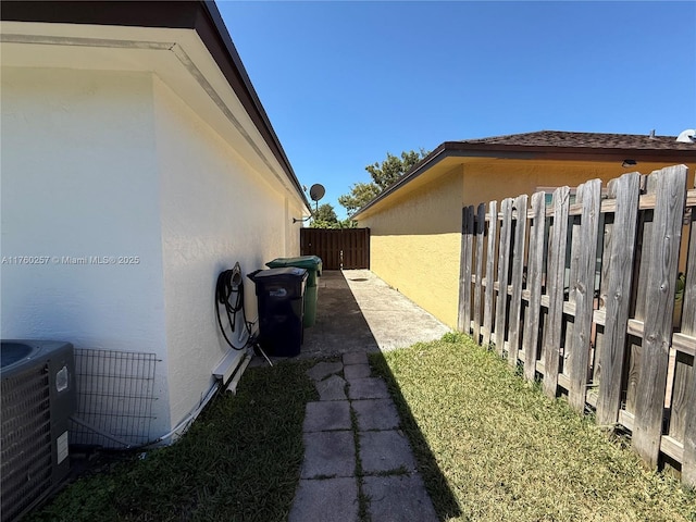 view of side of property with stucco siding, fence, and central air condition unit