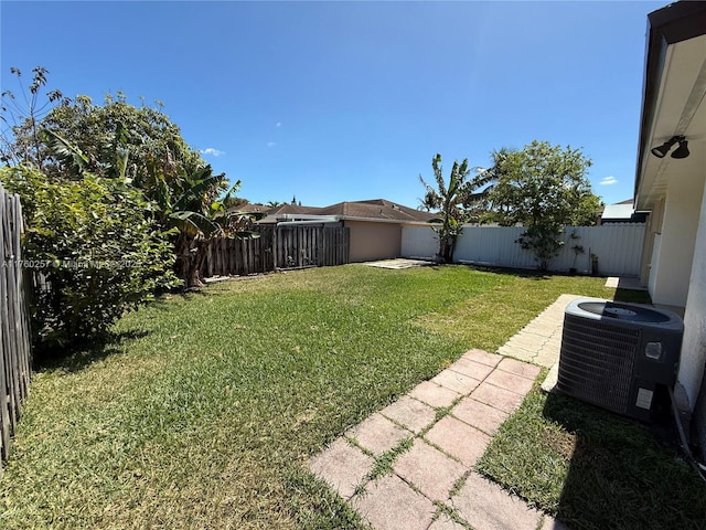 view of yard with a fenced backyard and central AC unit