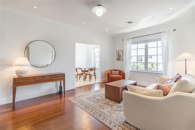 sitting room featuring visible vents, ornamental molding, baseboards, and wood finished floors