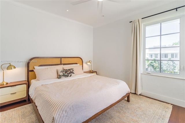 bedroom featuring baseboards, wood finished floors, a ceiling fan, and ornamental molding