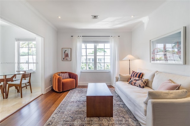 living area with a wealth of natural light, baseboards, wood finished floors, and ornamental molding