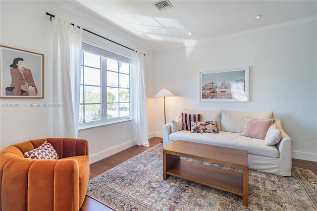 living area featuring wood finished floors, visible vents, baseboards, recessed lighting, and crown molding