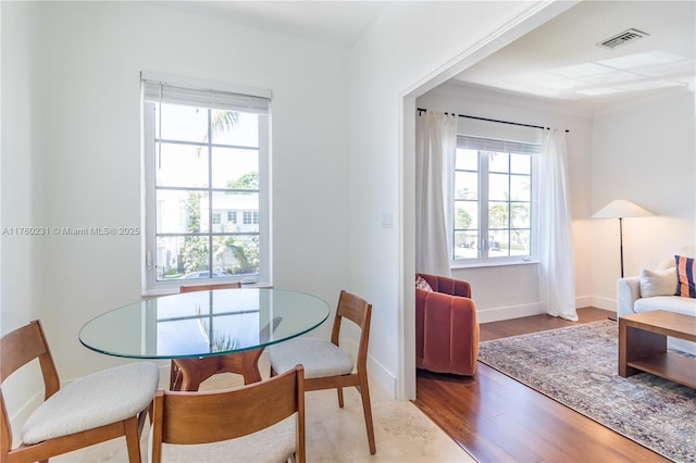 dining space with wood finished floors, visible vents, and baseboards