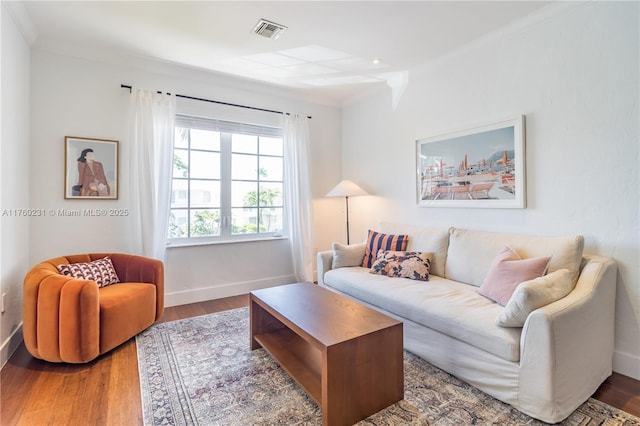 living area featuring visible vents, ornamental molding, baseboards, and wood finished floors