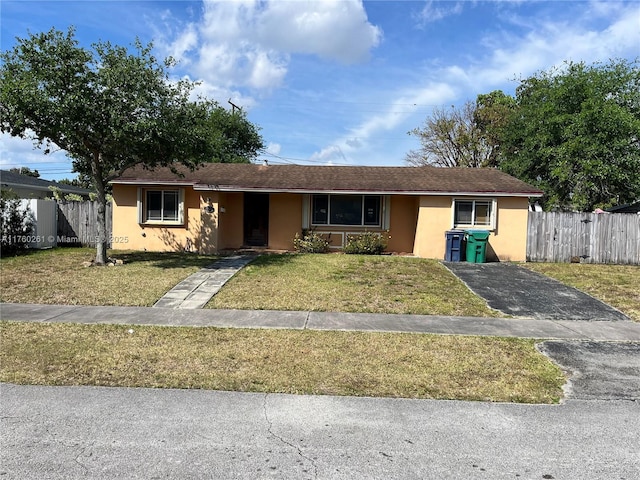 single story home featuring a front lawn, fence, and stucco siding