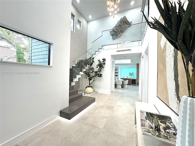 foyer featuring a wealth of natural light, stairway, baseboards, and a towering ceiling