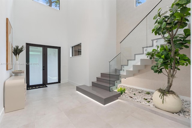 foyer featuring tile patterned floors, stairway, french doors, and a towering ceiling