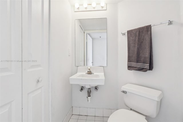 bathroom with tile patterned floors, baseboards, toilet, and a sink