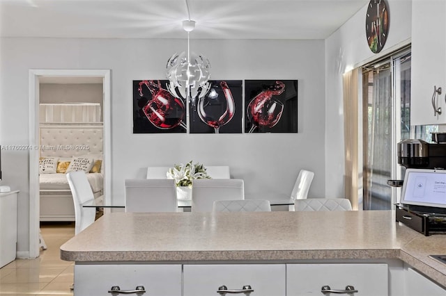 kitchen with light countertops, white cabinets, light tile patterned flooring, and a chandelier