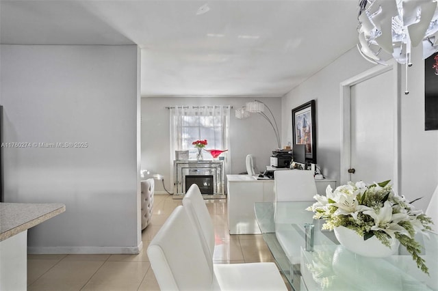 dining space featuring a glass covered fireplace, light tile patterned floors, and baseboards