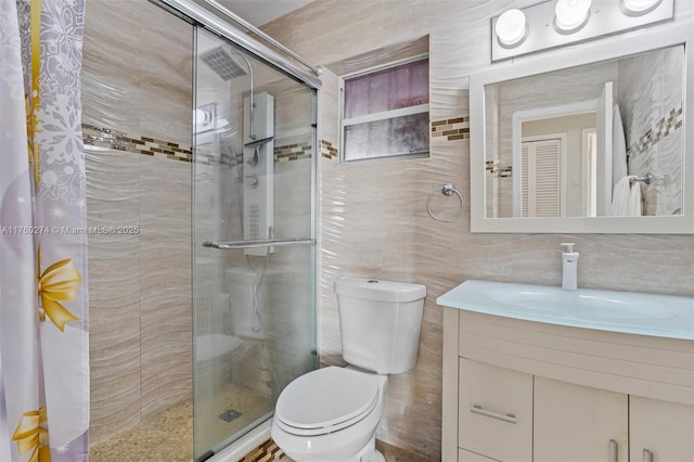 bathroom with a shower stall, vanity, toilet, and tile walls