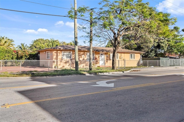 ranch-style house with stucco siding and a fenced front yard