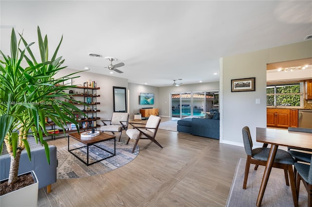 living area featuring baseboards, light wood-style floors, ceiling fan, and visible vents