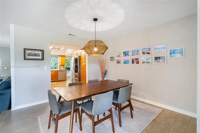 dining room featuring light wood-style floors, visible vents, and baseboards