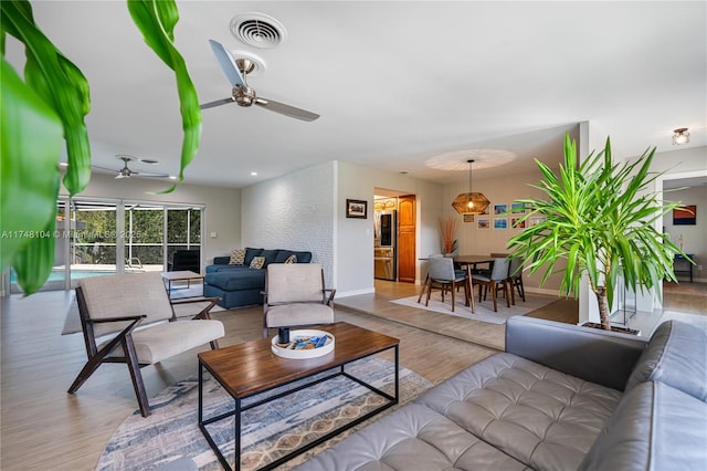 living room with a ceiling fan, wood finished floors, visible vents, and baseboards