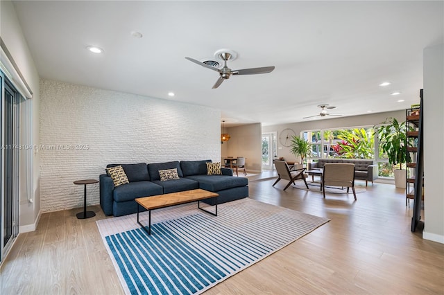 living room with recessed lighting, wood finished floors, and brick wall