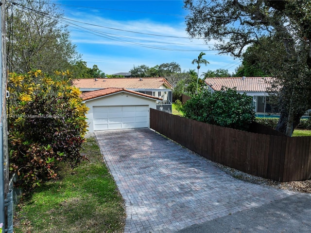 view of front of home with stucco siding, decorative driveway, fence, an attached garage, and a tiled roof