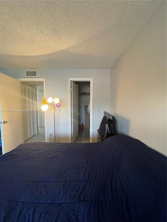 unfurnished bedroom featuring visible vents, a textured ceiling, and tile patterned flooring